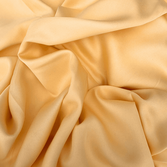 Tejido de algodón de bambú suave y sedoso en tono beige claro con pliegues naturales