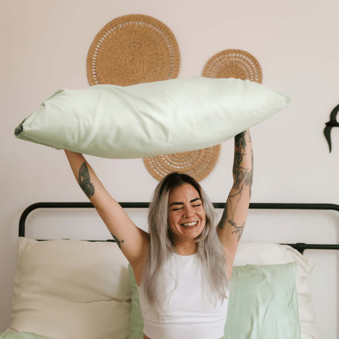 Woman holding white comfortable bamboo bedding on a bed
