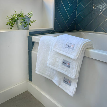 Three-piece white bamboo towel set by bathtub – bath, hand and face towels, soft, absorbent and sustainable