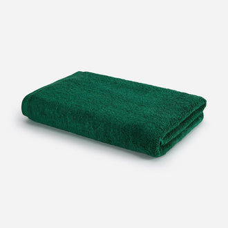 Toalla de baño verde bosque doblada sobre fondo blanco, diseño Wabi-sabi de Momo Cotton