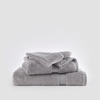 Juego de toallas de bambú gris apiladas sobre fondo blanco, incluye toallas de cara, mano y baño