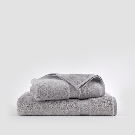 Juego de toallas de bambú gris apiladas sobre fondo blanco mostrando toallas de cara, mano y baño
