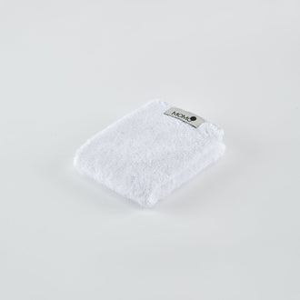 Toalla de bambú blanca con etiqueta Momo Cotton sobre fondo claro, vista angular