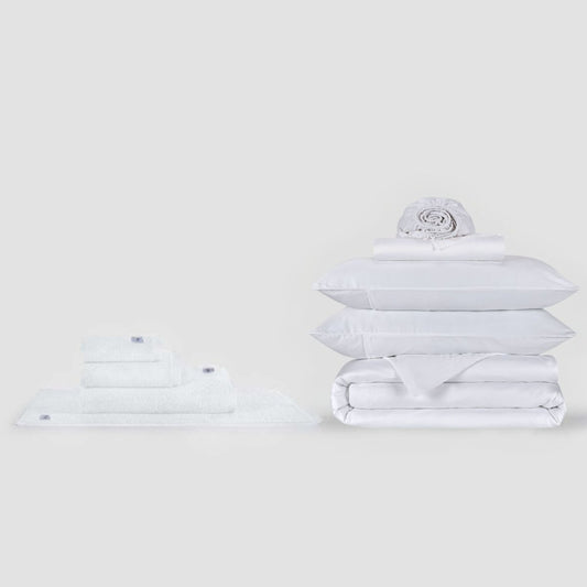 Conjunto completo de sábanas blancas y colección de toallas Momo Cotton exhibido en fondo neutro