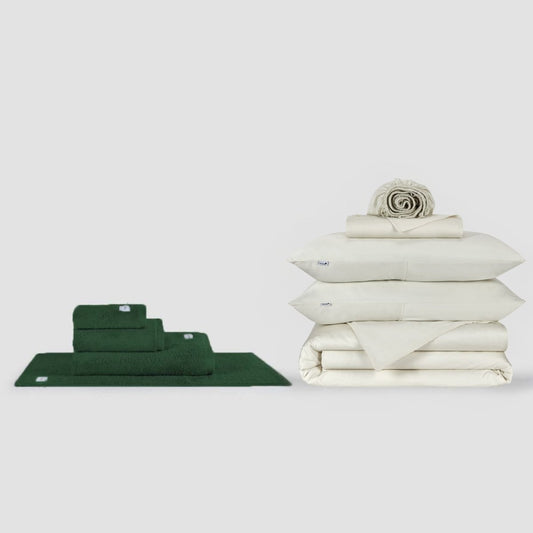 Conjunto de toallas verdes y sábanas blancas en fondo neutro de Momo Cotton
