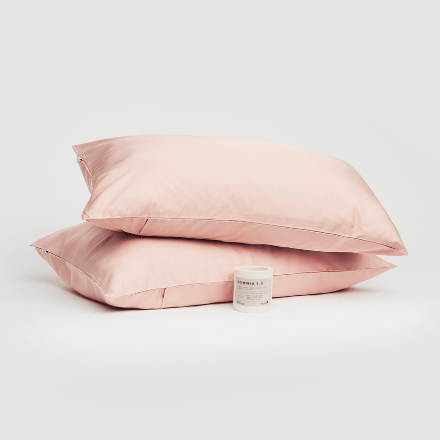 Par de fundas de almohada de algodón rosa presentadas con producto Somnia 1.0 sobre fondo blanco