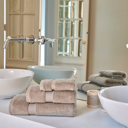 Conjunto de toallas de bambú Alba apiladas en el lavabo de un baño elegante con grifería moderna