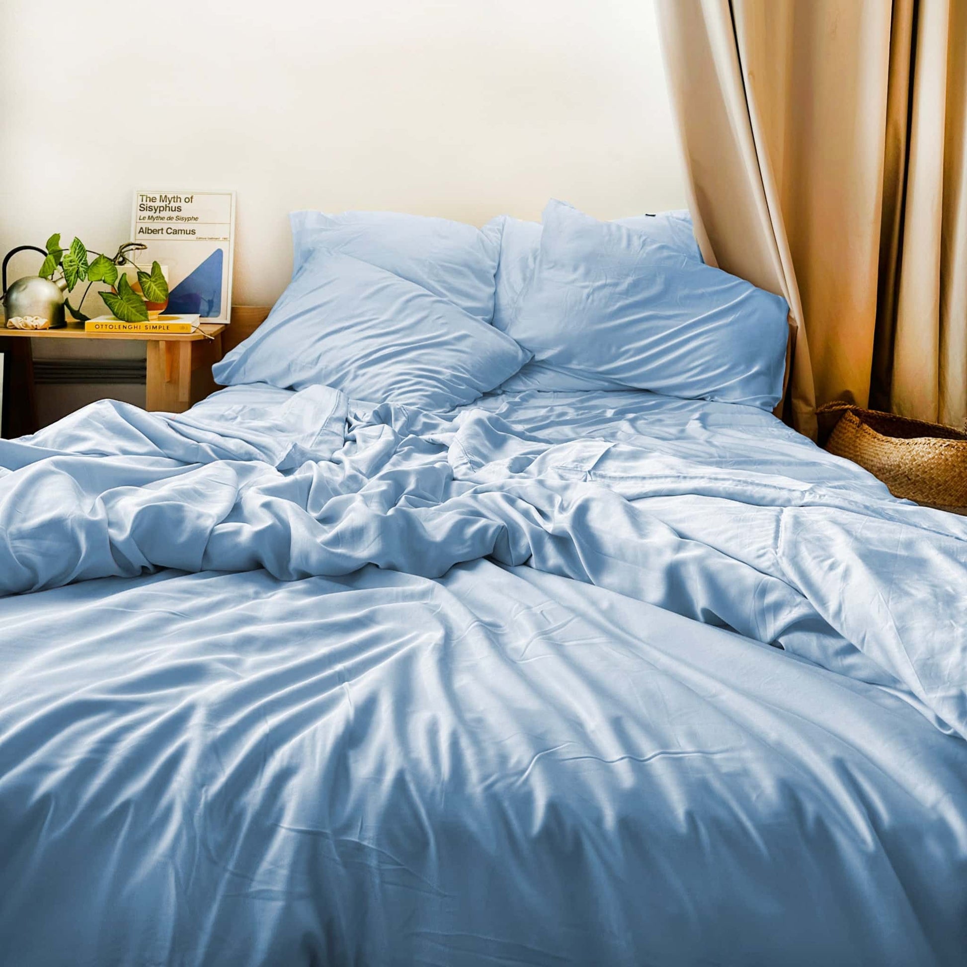 Messy bed with blue bamboo sheets and pillows – soft, breathable and sustainable bedding