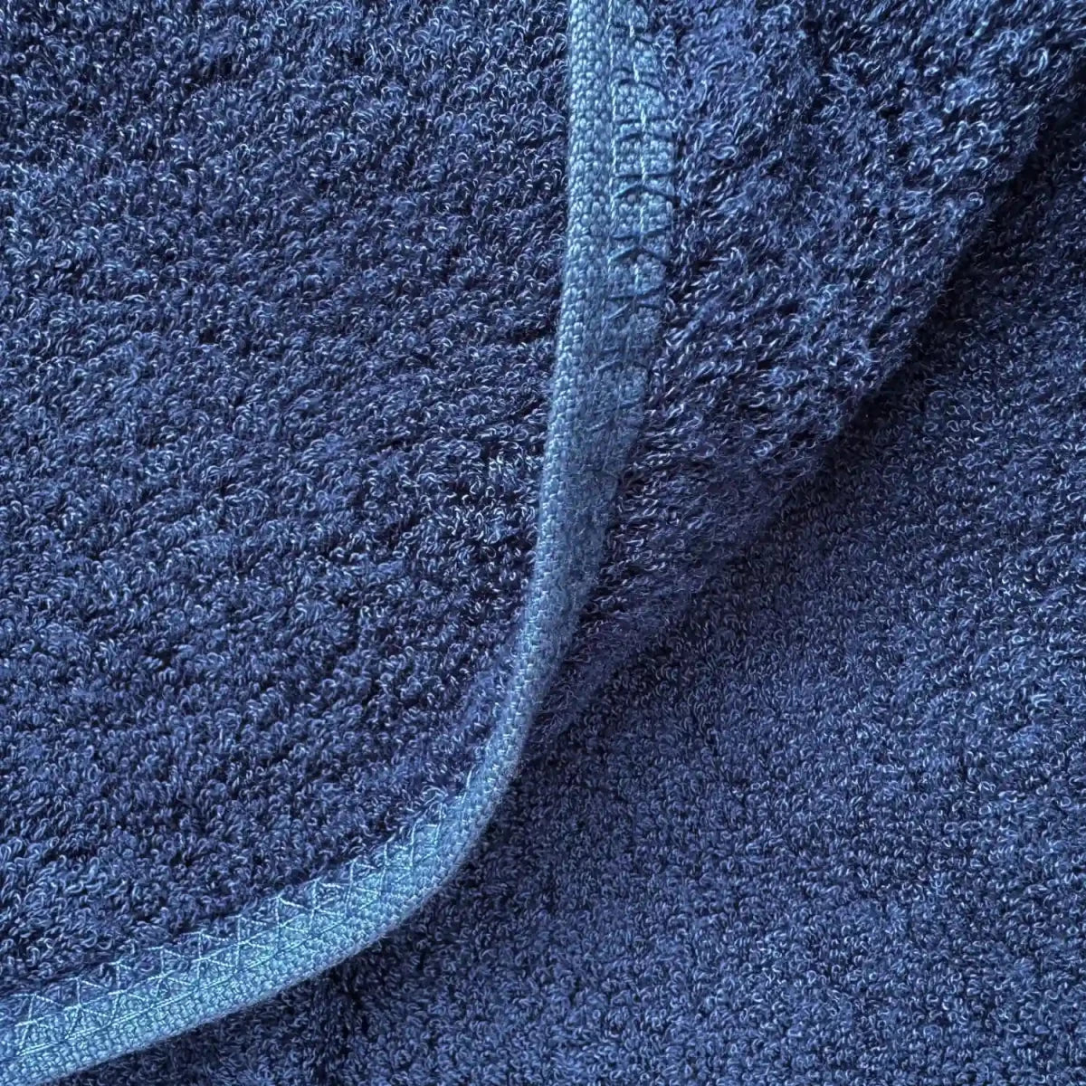 Conjunto de toallas de bambú azul oscuro mostrando detalle de textura y capas dobladas con iluminación neutra