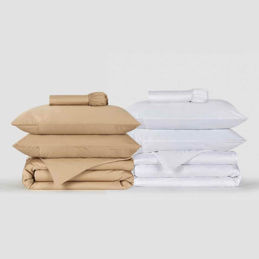 Juegos de ropa de cama beige y blanco apilados ordenadamente, con almohadas y fundas de edredón Momo Cotton