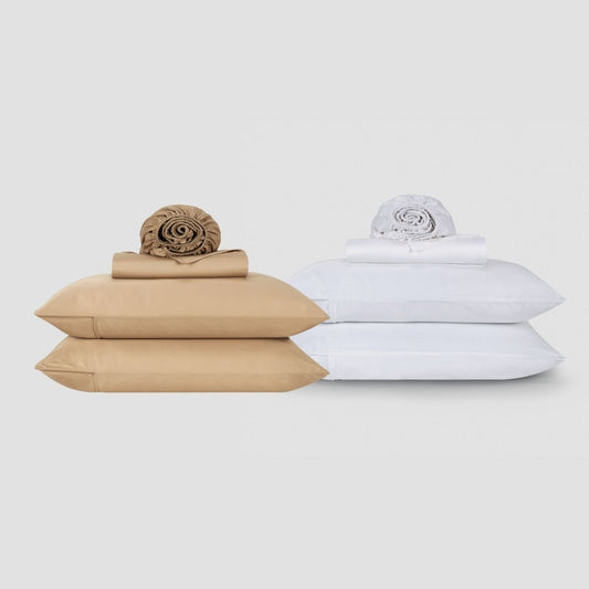 Juegos de sábanas de algodón Momo beige y blanco apilados con ropa de cama y almohadas enrolladas sobre fondo neutro