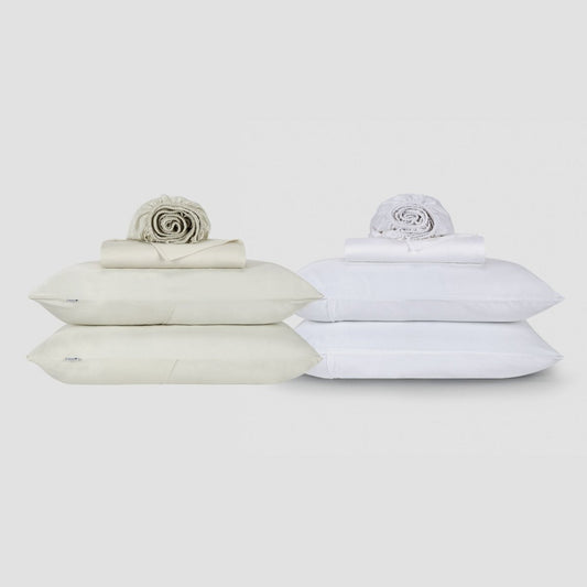 Dos juegos de ropa de cama Jogo Lençol de Cima en crema y blanco, apilados con almohadas