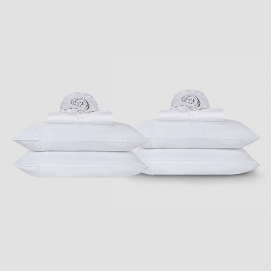 Dos sábanas blancas de algodón apiladas con ropa de cama enrollada sobre fondo neutro de Momo Cotton