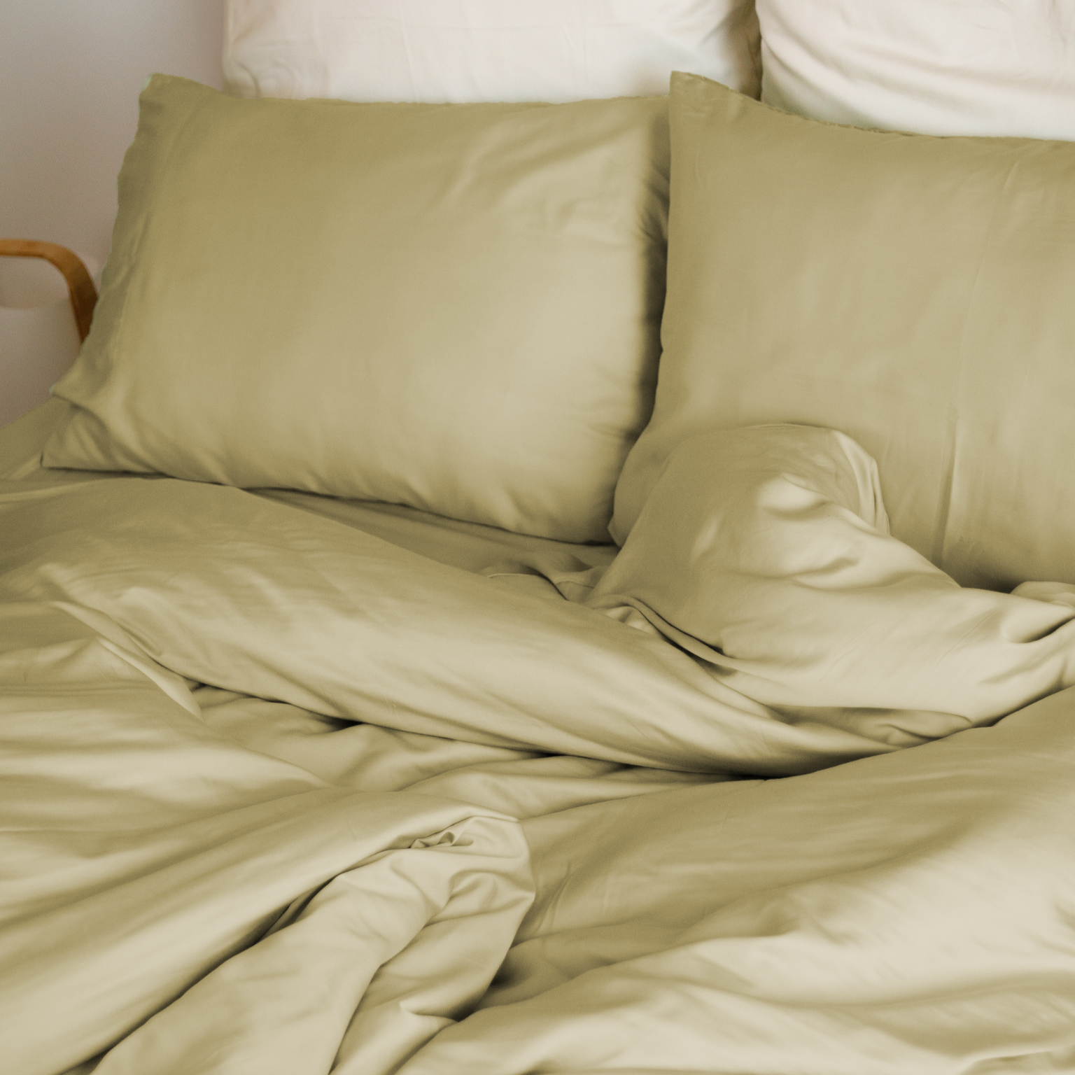 Cama com capa de edredão bege areia, almofadas bege e almofadas brancas atrás – macio e sustentável