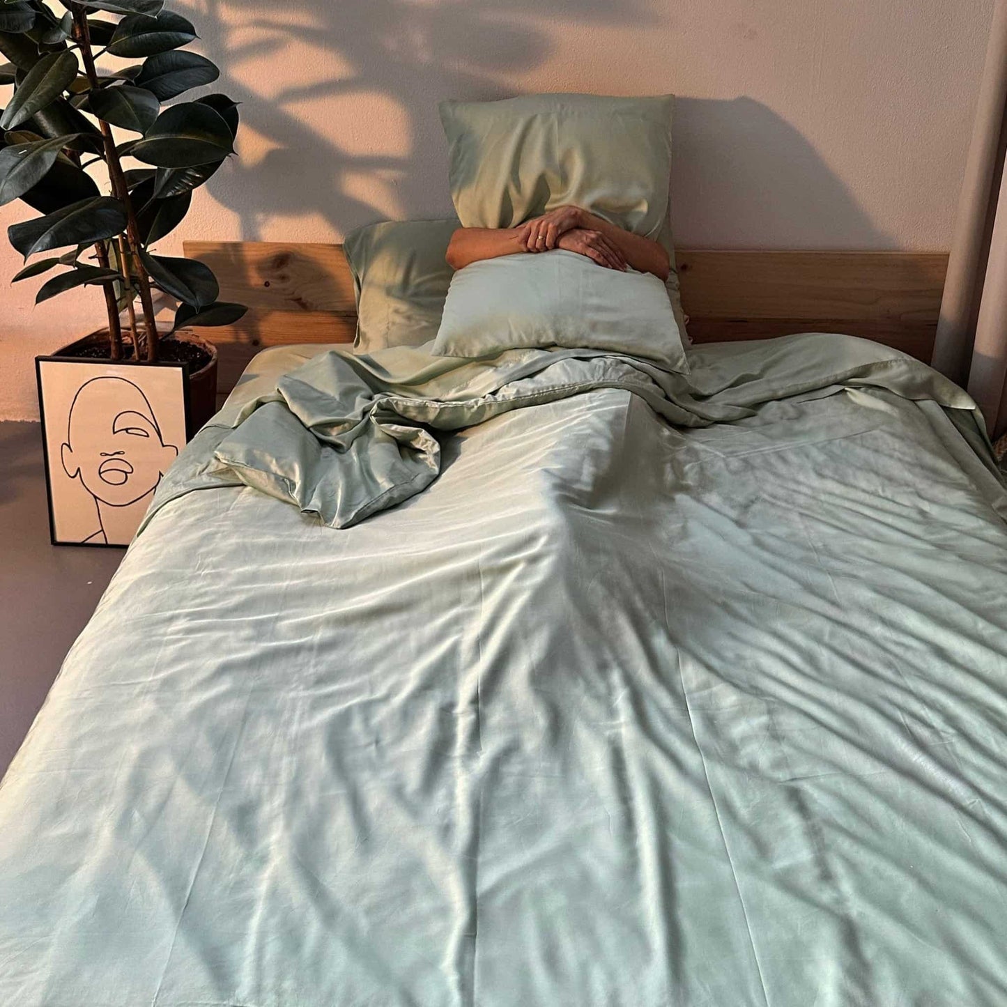 Complete green bamboo bedding set with woman holding pillow – duvet, sheets and pillows, soft, breathable and sustainable