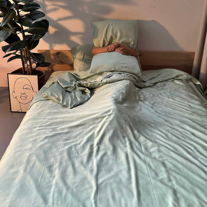Complete green bamboo bedding set with woman holding pillow – duvet, sheets and pillows, soft, breathable and sustainable