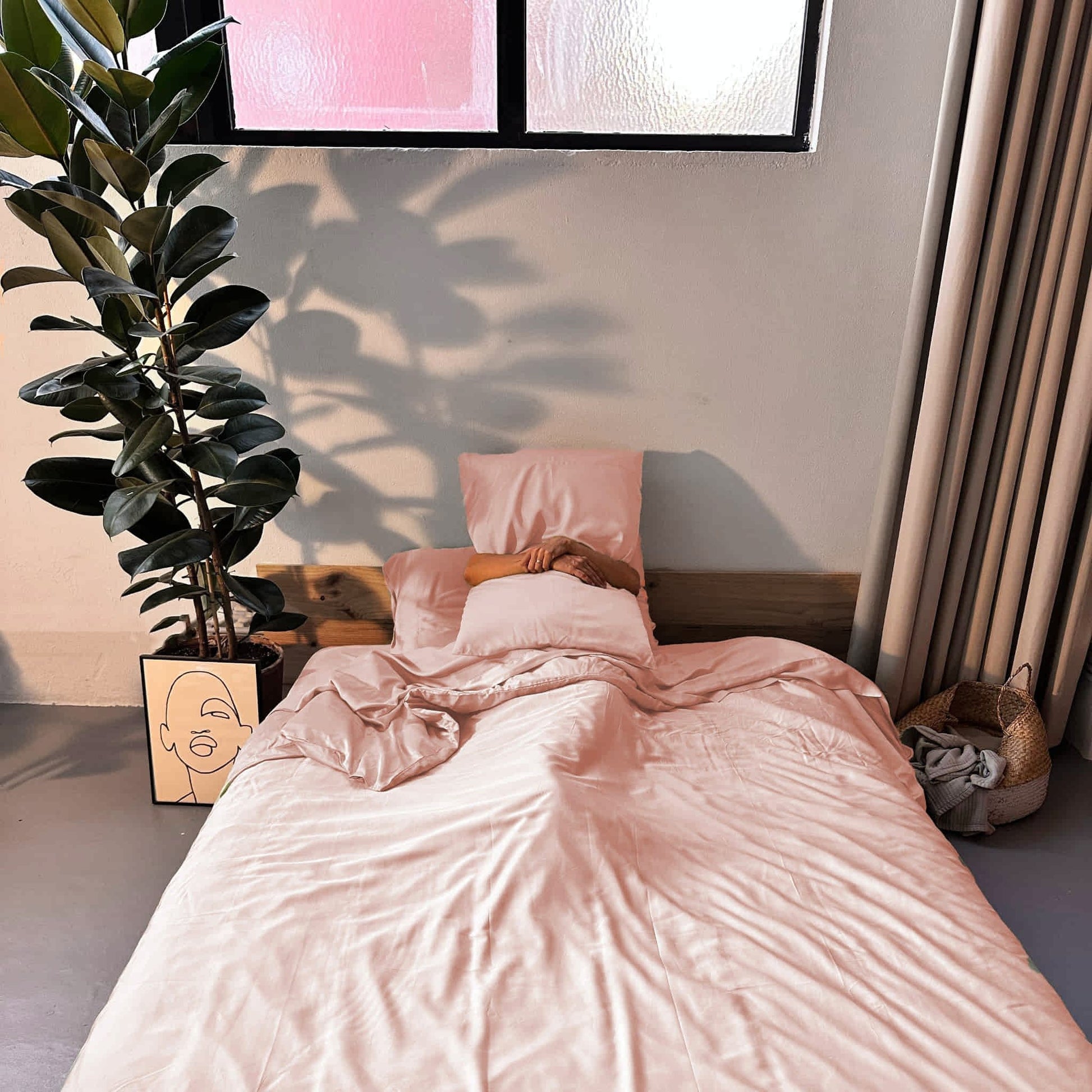 Complete bamboo bedding set in lemonade pink on bed with woman – soft, breathable and sustainable
