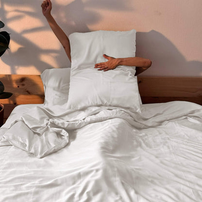 Complete white bamboo bedding set with woman holding pillow – duvet, sheets and pillows, soft, breathable and sustainable