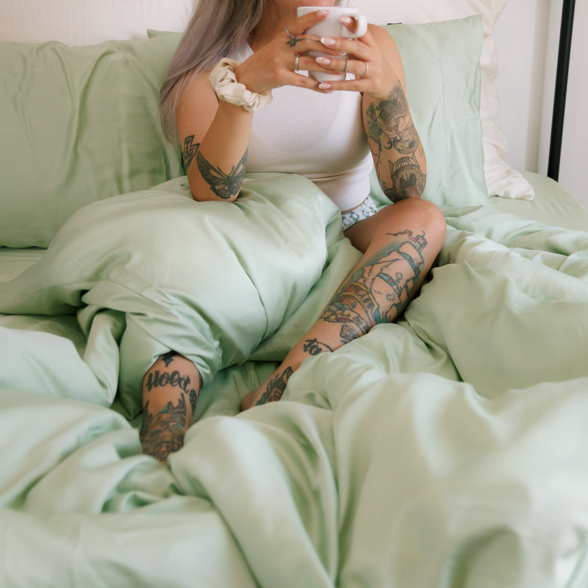 Juego de funda nórdica verde menta en cama con ropa blanca, mostrando la suavidad y conforto del tejido