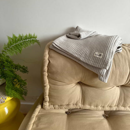 Grey bamboo blanket on beige couch – soft, breathable and sustainable
