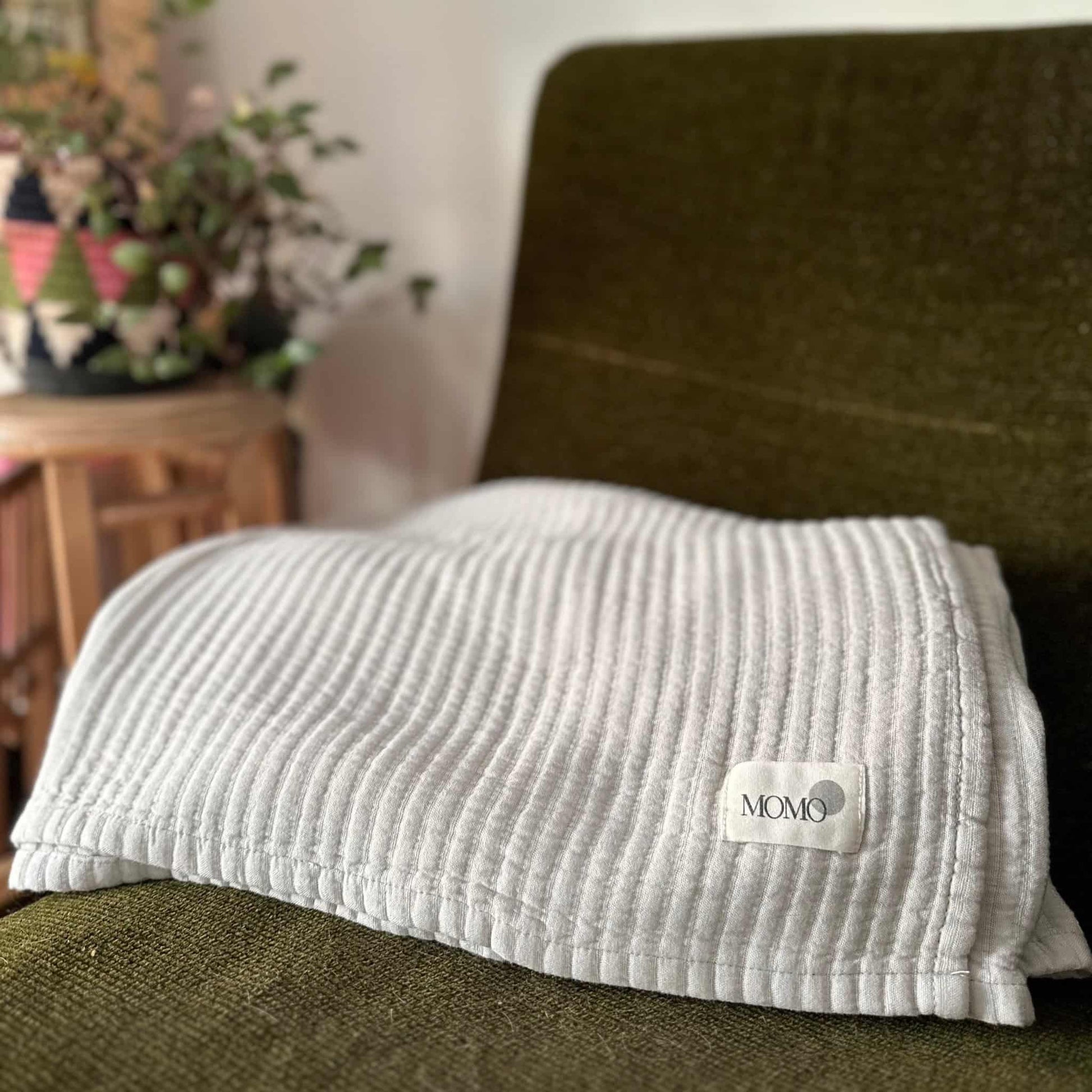 Grey bamboo blanket on dark couch – soft, breathable and sustainable