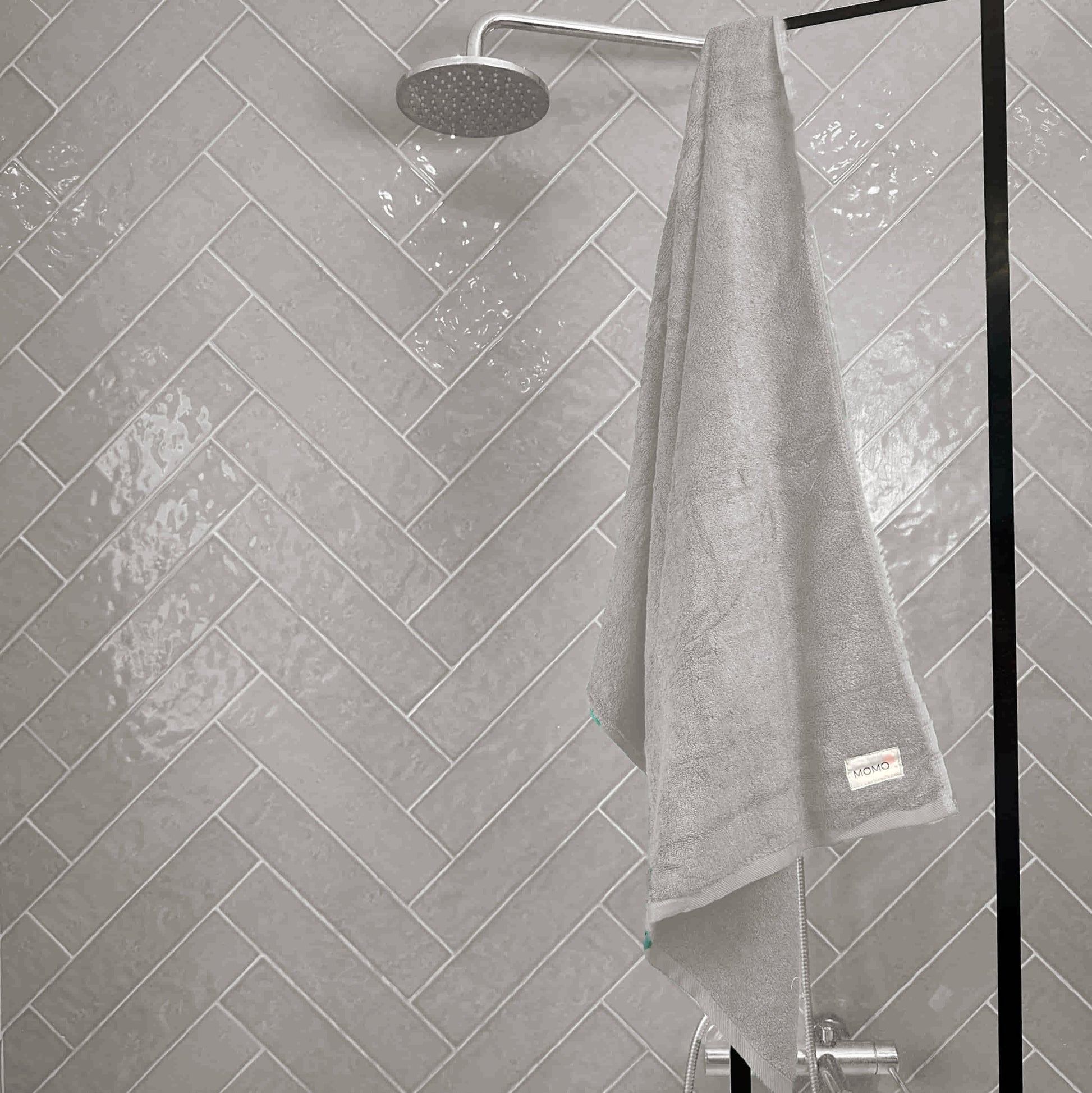 Grey bamboo towel on shower grey background – soft, absorbent and sustainable