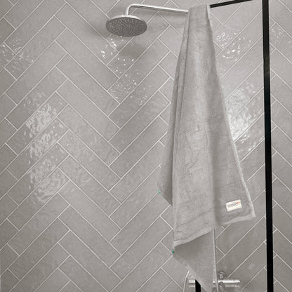 Grey bamboo towel on shower grey background – soft, absorbent and sustainable