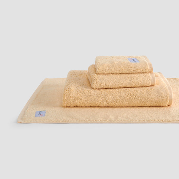 Beige bamboo towel set from Wabi-sabi stacked on white background, showing face, hand and bath towels with brand
